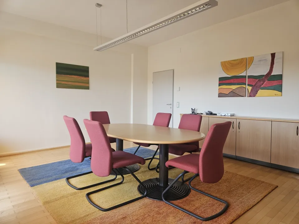 Besprechungsraum der Kanzlei mit Besprechungstisch und roten Stühlen